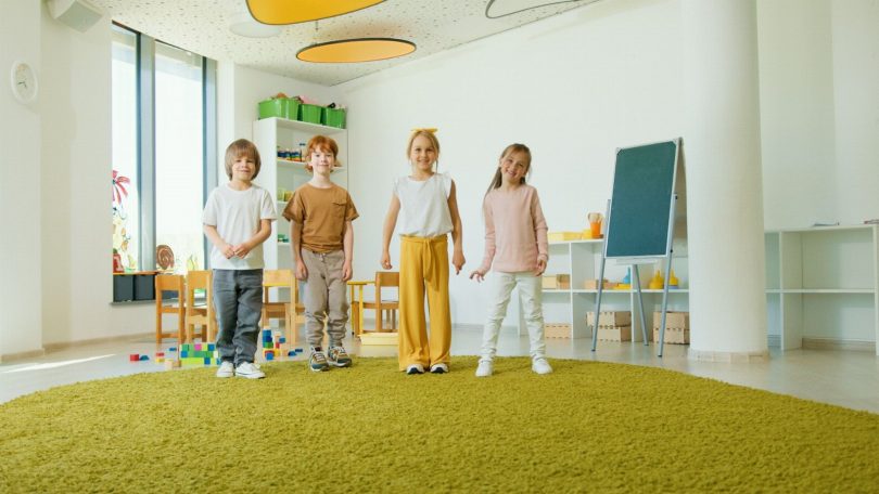 Técnico com equipamentos realizando inspeção de controle de pragas em sala de creche com brinquedos e mesas infantis