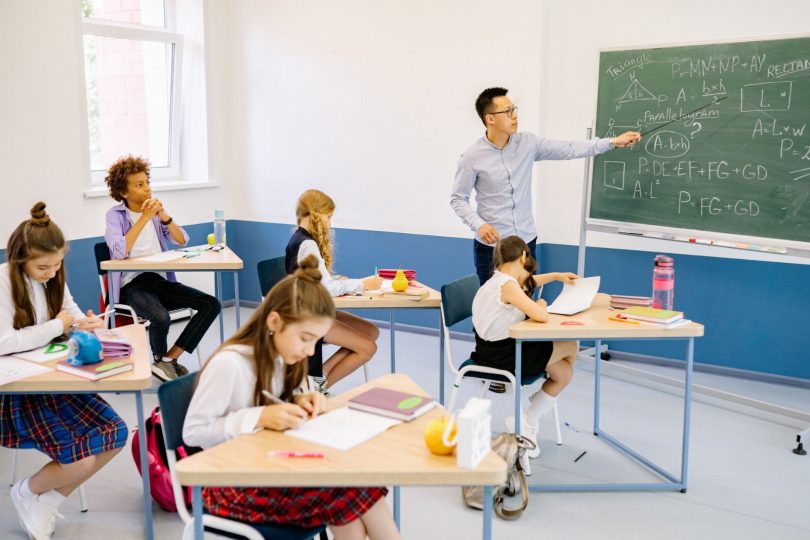 Técnico de controle de pragas inspecionando sala de aula com armadilhas e checklist