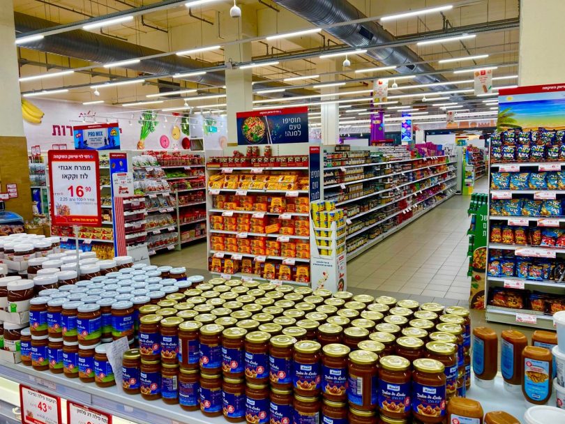 Técnico com equipamento aplicando controle de pragas em corredor de supermercado
