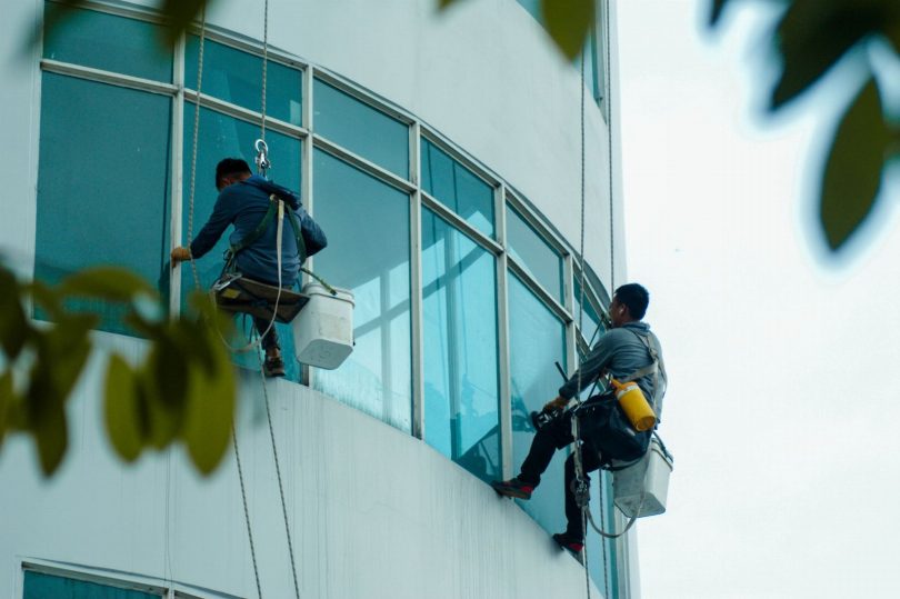 Técnico uniformizado limpando interior de caixa d'água metálica em cobertura de prédio comercial