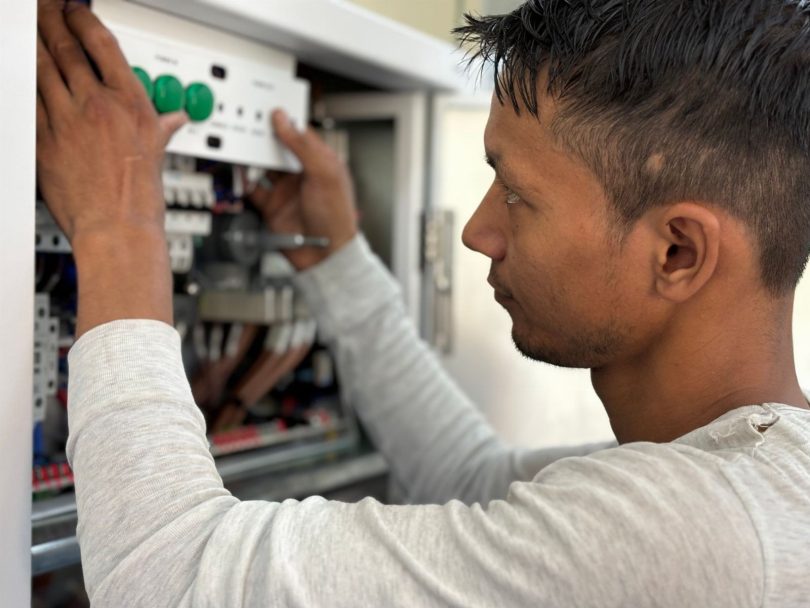 Técnico instalando sensor IoT e armadilha digital em corredor de galpão com pallets